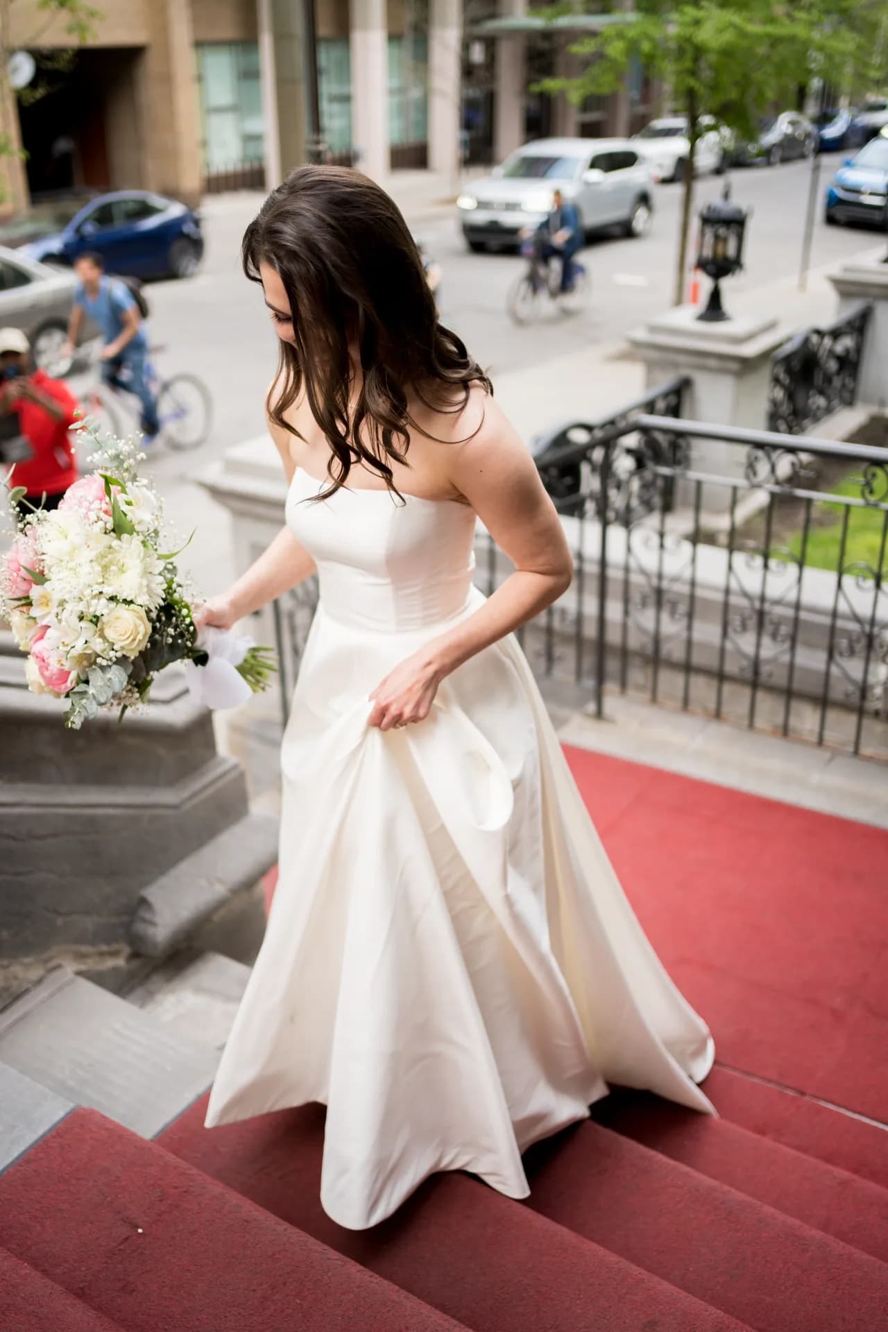 La mariée descendant un escalier extérieur, bouquet à la main